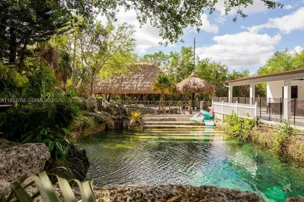 a view of swimming pool with lawn chairs and plants