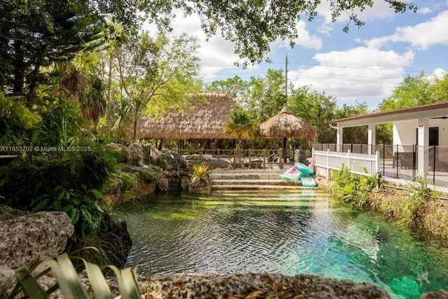 a view of swimming pool with lawn chairs and plants
