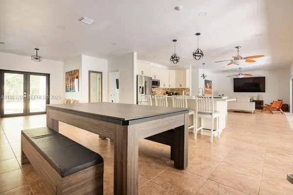 a dining hall with stainless steel appliances kitchen island granite countertop a table and chairs in it
