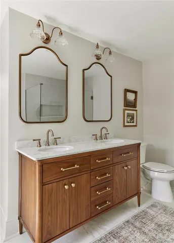 a bathroom with a toilet sink double vanity and mirror