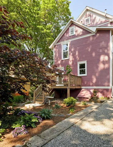 a view of a house with a small yard plants and large tree