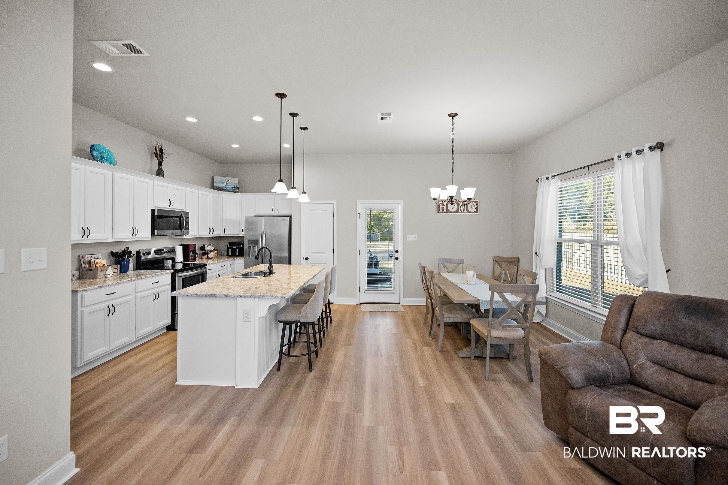 1077 Stella Road Foley, AL 36535 - Photo 11 of 27 Kitchen featuring a breakfast bar, an island with sink, stainless steel appliances, white cabinets, and plenty of natural light