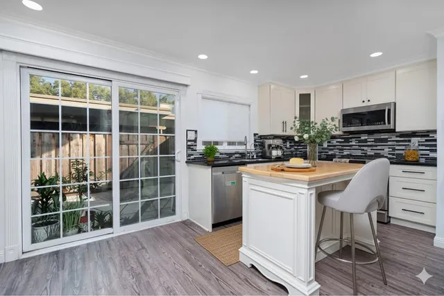 a kitchen with kitchen island granite countertop a stove a refrigerator a sink a dining table and chairs with wooden floor