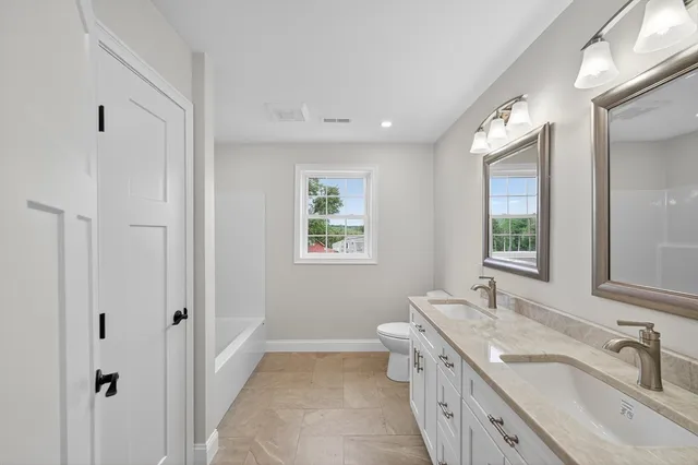 a bathroom with a double vanity sink a mirror and a bathtub
