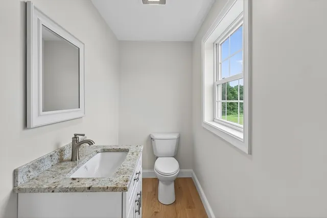 a bathroom with a granite countertop toilet a sink and a mirror
