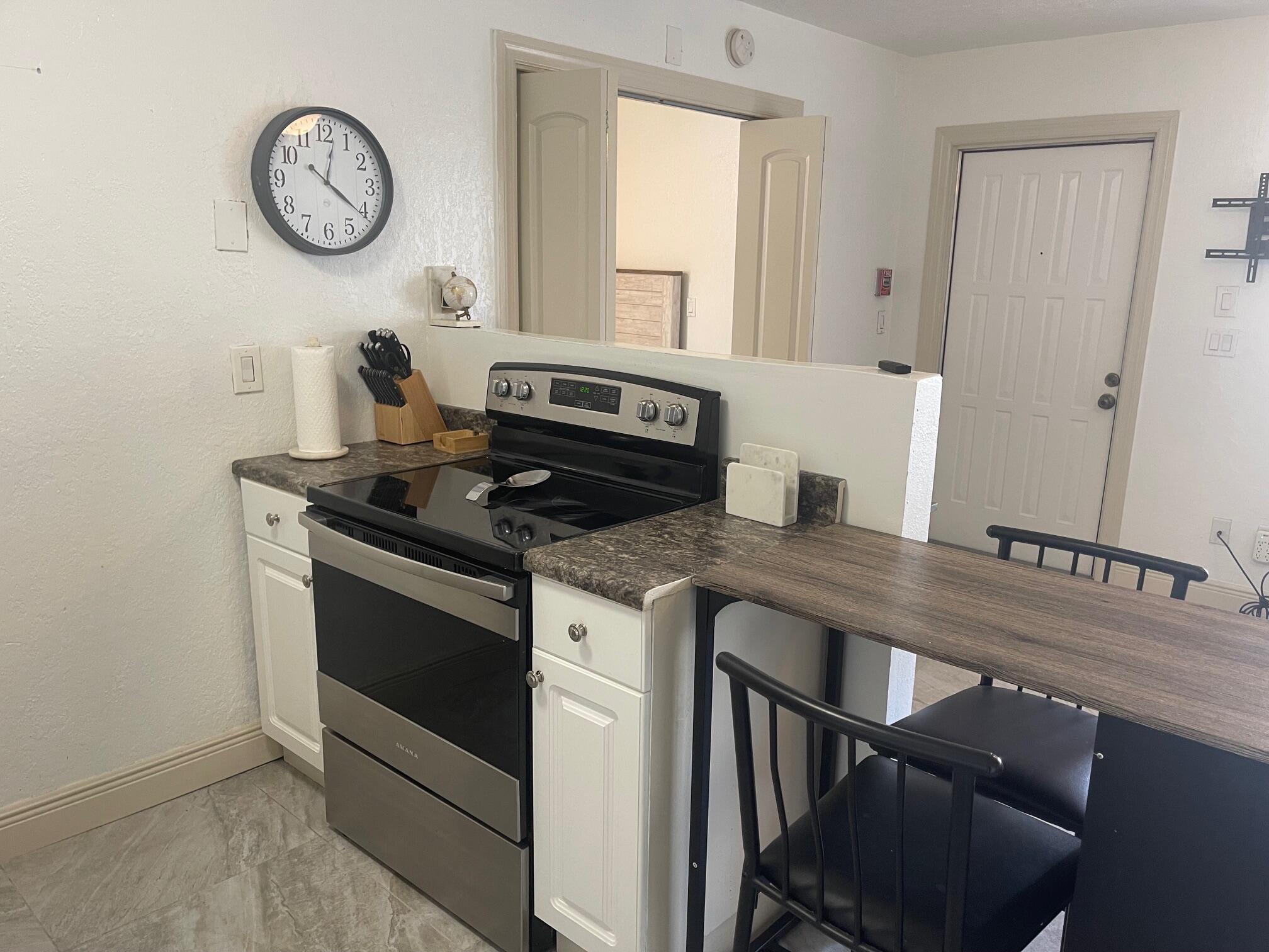 641 Executive Center Drive, Unit P105 West Palm Beach, FL 33401 - Photo 4 of 21 a kitchen with a stove and a clock on the wall