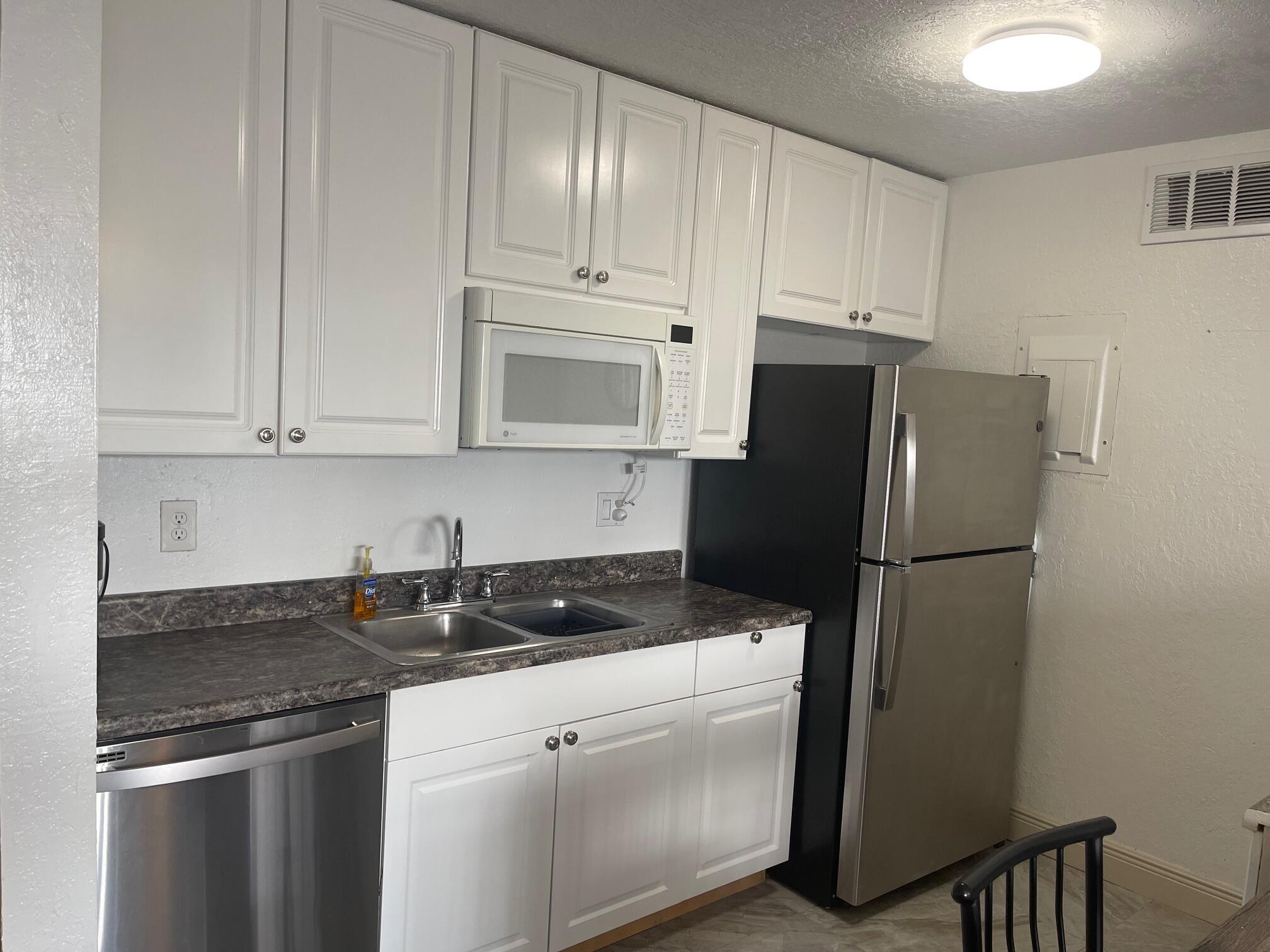 641 Executive Center Drive, Unit P105 West Palm Beach, FL 33401 - Photo 5 of 21 a kitchen with a refrigerator sink and cabinets