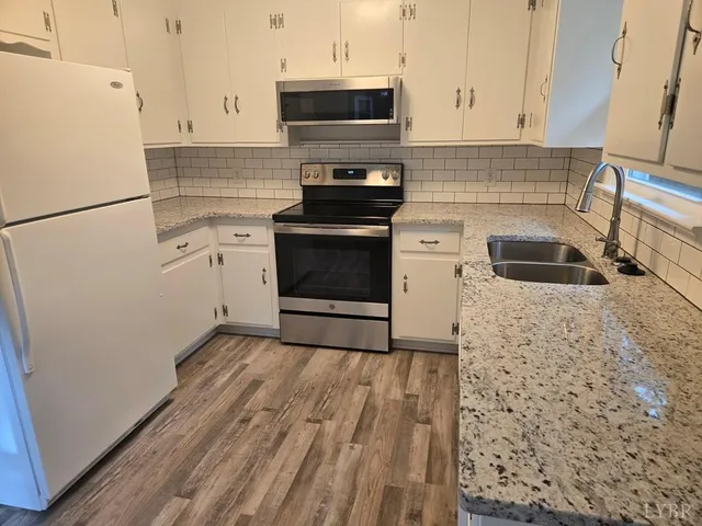 a kitchen with granite countertop a sink stove and refrigerator