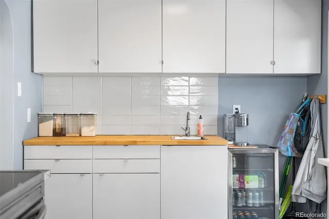 a room with stainless steel appliances granite countertop a sink a stove and white cabinets