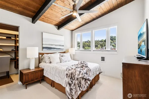 a bedroom with a bed a dresser and a large window