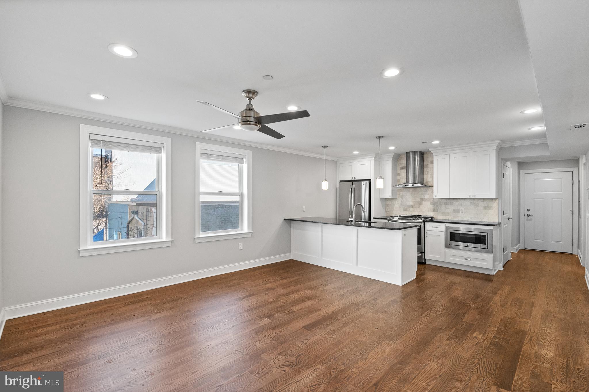 988 North Marshall Street, Unit 2R Philadelphia, PA 19123 - Photo 12 of 29 a large kitchen with stainless steel appliances kitchen island granite countertop a stove a sink a refrigerator and white cabinets with wooden floor