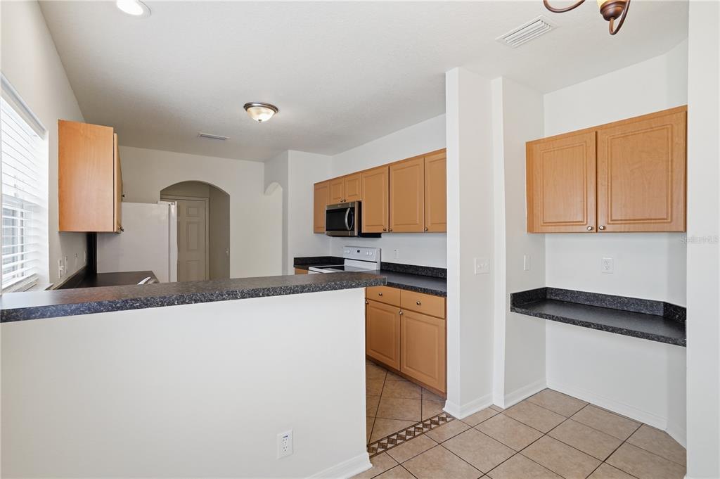 4155 Day Bridge Place Ellenton, FL 34222 - Photo 18 of 42 a kitchen with granite countertop a refrigerator and a stove top oven