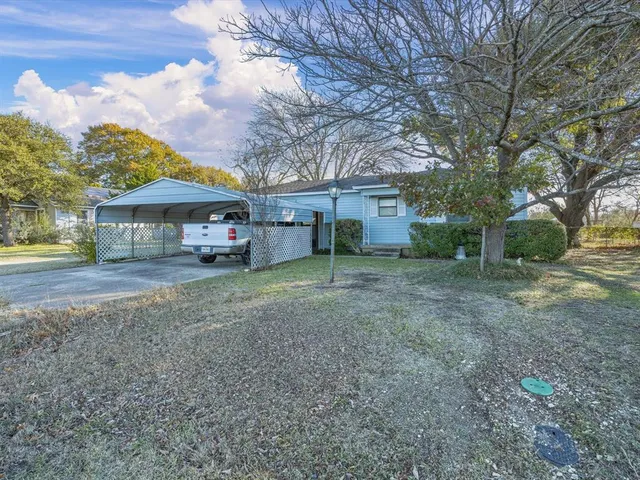 a front view of a house with a yard and large tree