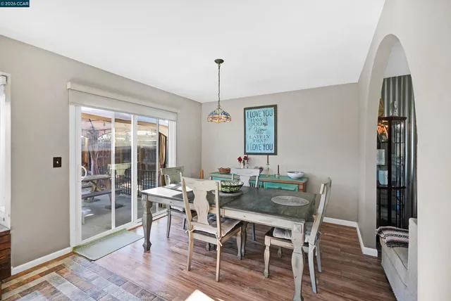 a kitchen with stainless steel appliances granite countertop a stove top oven a dining table and chairs with the wooden floor