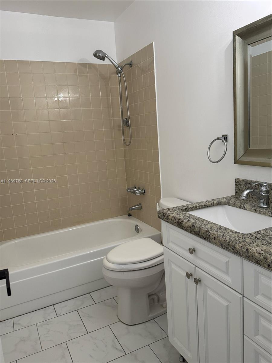 15332 Southwest 80th Lane, Unit 15332 Miami, FL 33193 - Photo 12 of 16 a bathroom with a granite countertop toilet a sink and bathtub