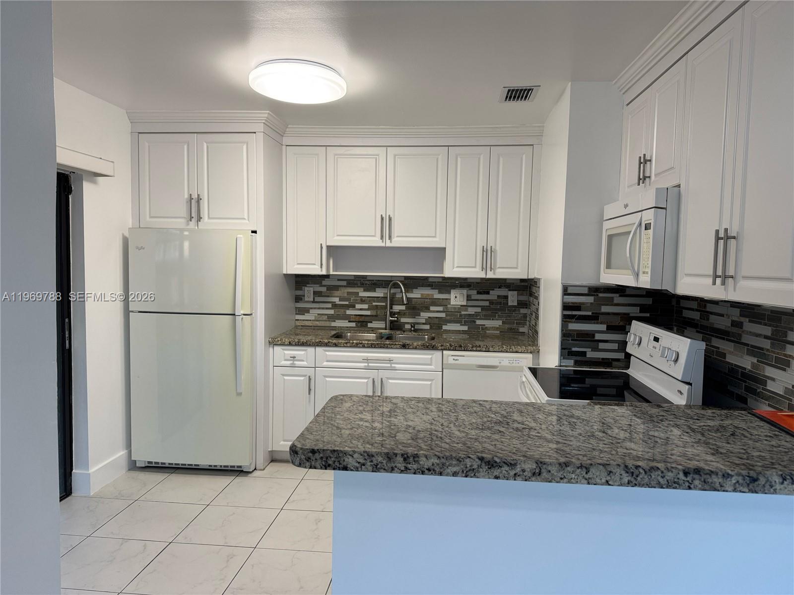 15332 Southwest 80th Lane, Unit 15332 Miami, FL 33193 - Photo 3 of 16 a kitchen with granite countertop a refrigerator sink and cabinets