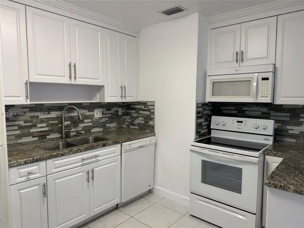 a kitchen with white cabinets and appliances
