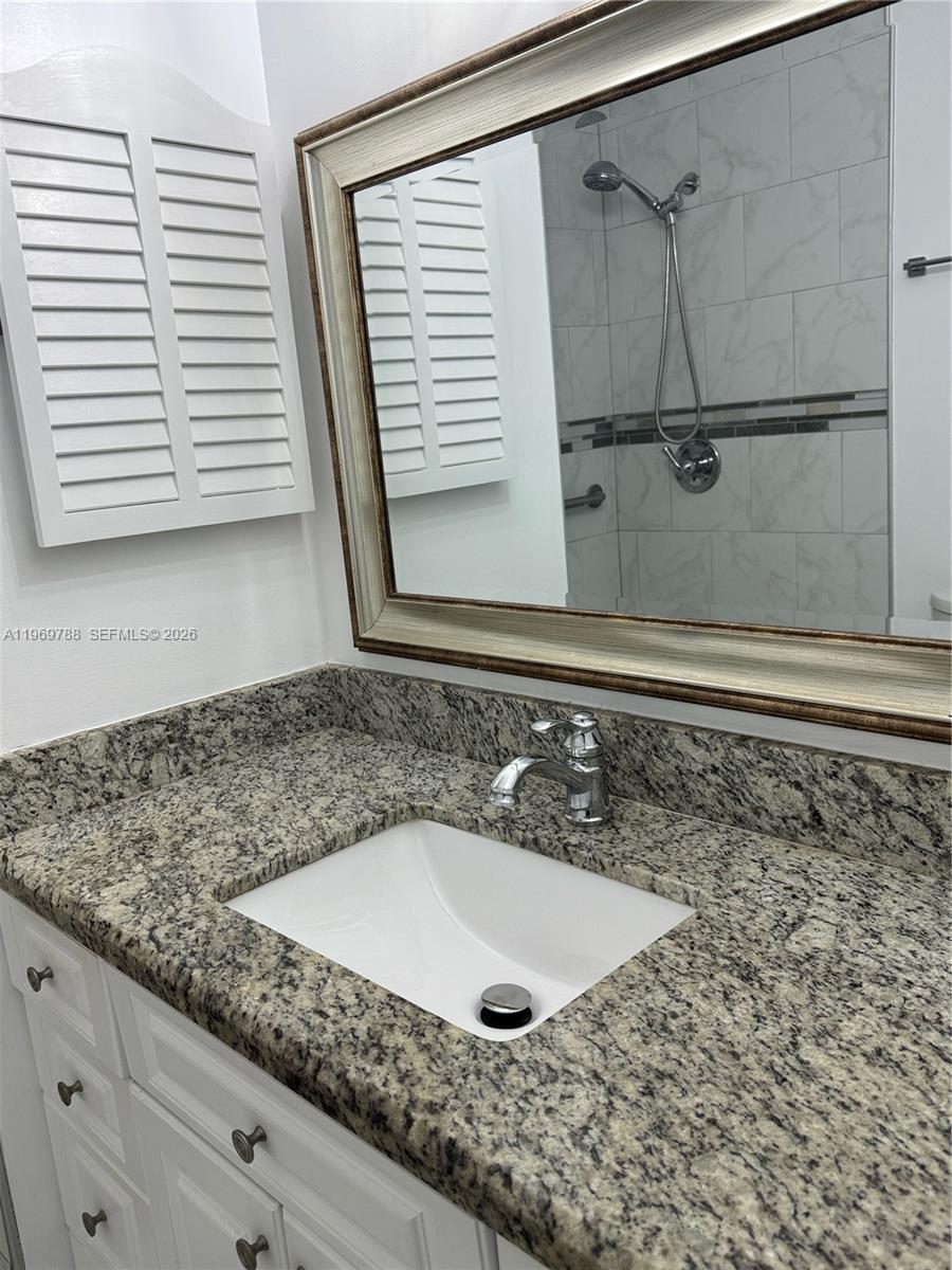 15332 Southwest 80th Lane, Unit 15332 Miami, FL 33193 - Photo 9 of 16 a bathroom with a granite countertop sink and a mirror