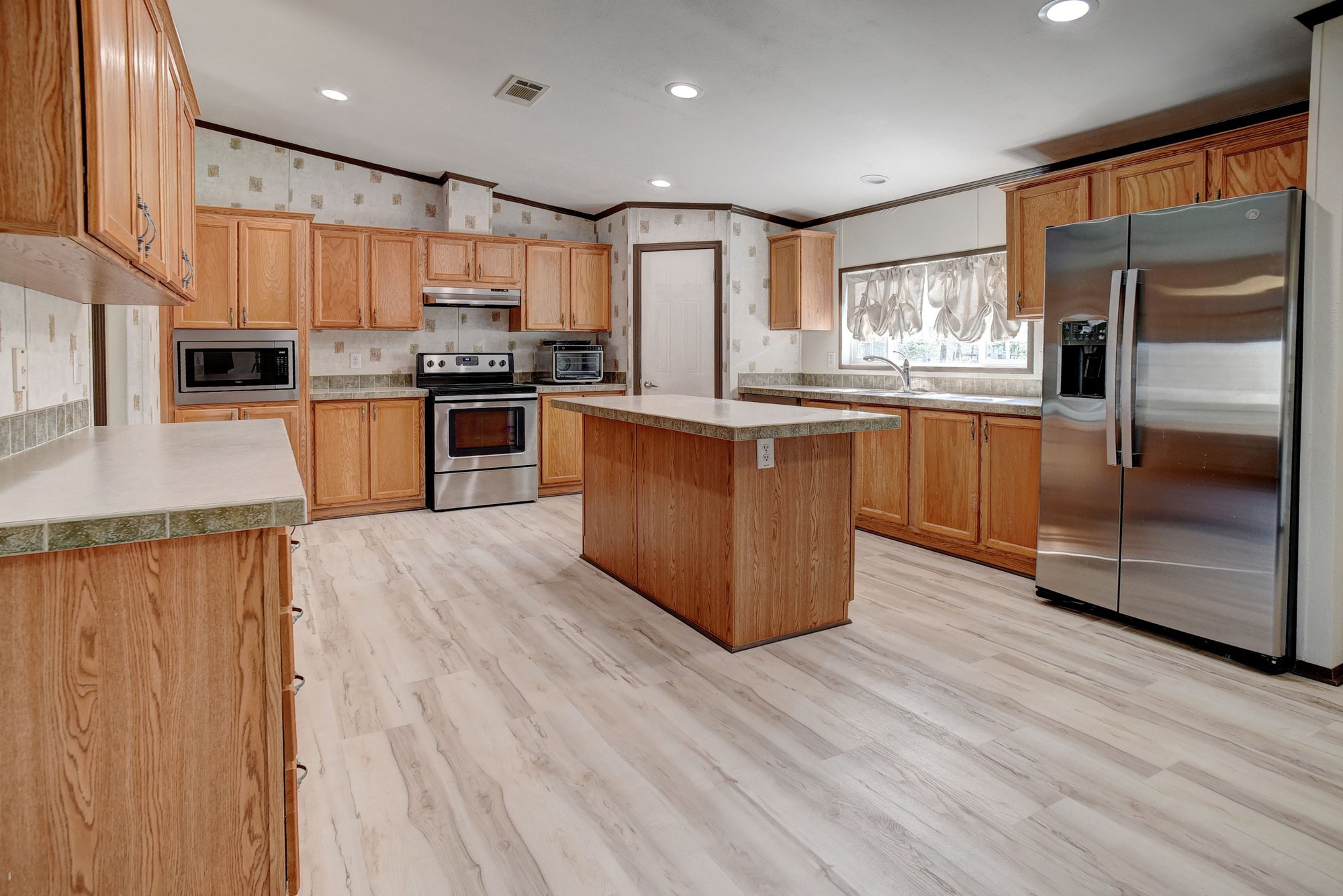 552 South Old Potato Road Paige, TX 78659 - Photo 10 of 40 a kitchen with stainless steel appliances granite countertop a refrigerator a stove top oven a sink and dishwasher with wooden floor