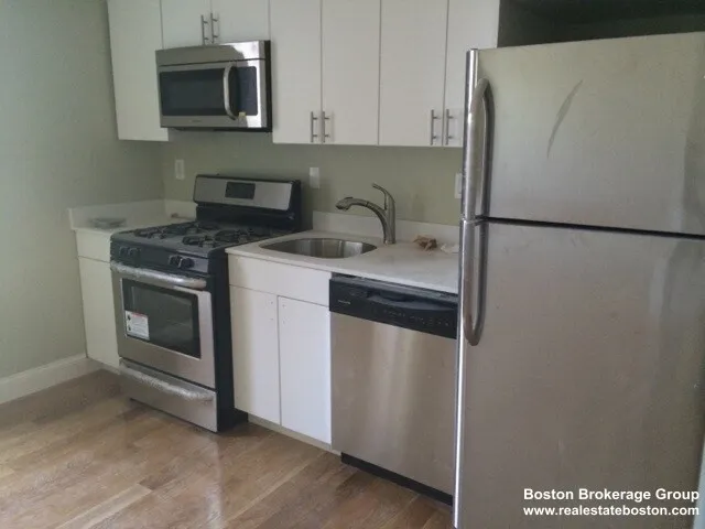 a kitchen with stainless steel appliances white cabinets and a refrigerator
