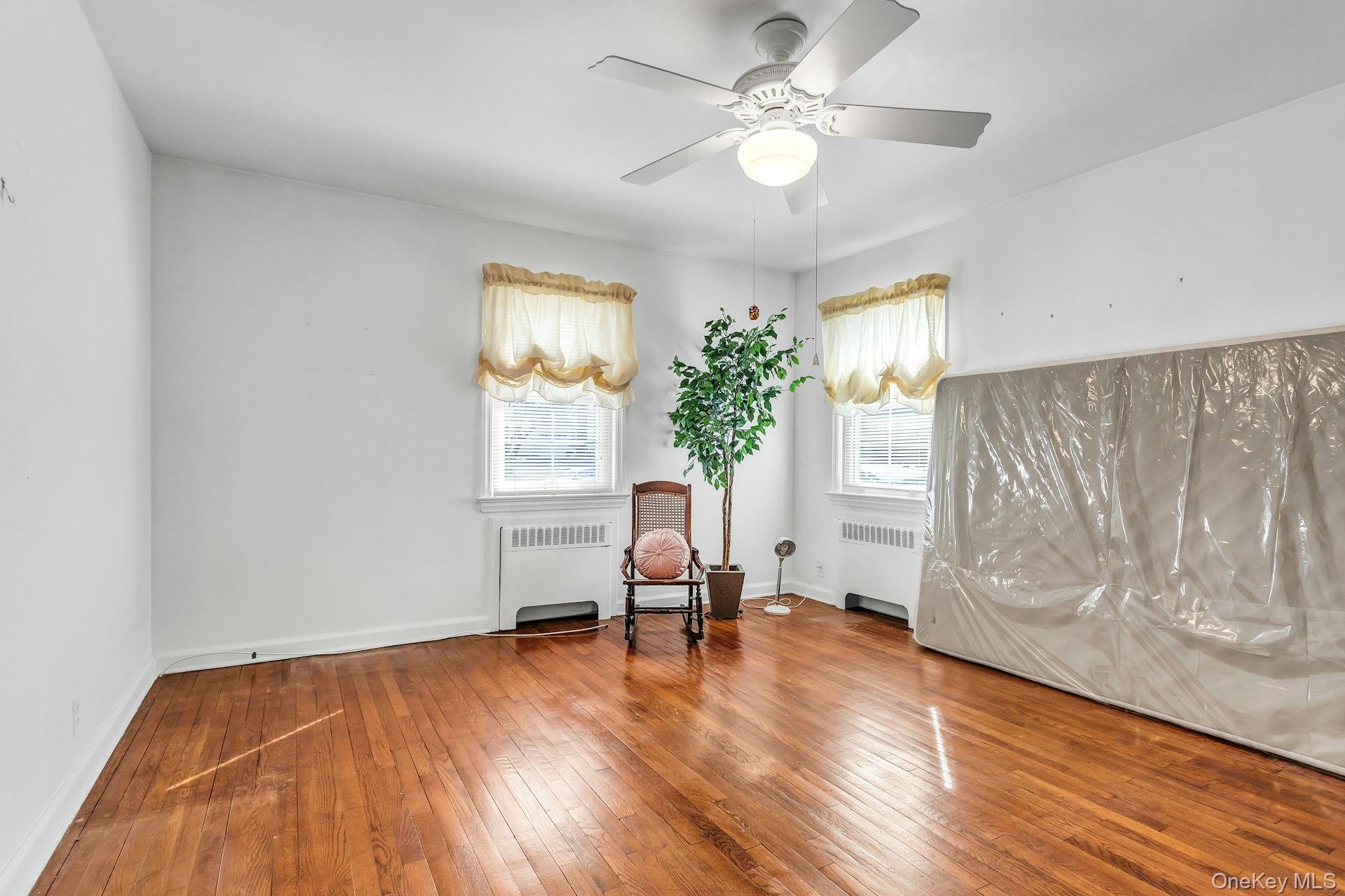 5 Sherwood Road Glen Cove, NY 11542 - Photo 16 of 26 Primary Bedroom featuring radiator heating unit, hardwood / wood-style floors, and ceiling fan