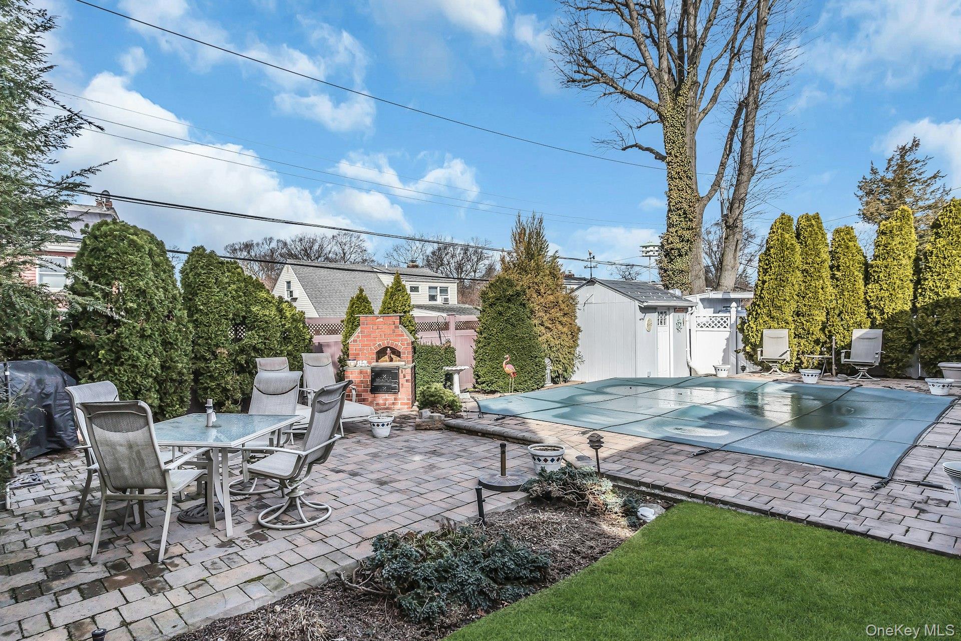 5 Sherwood Road Glen Cove, NY 11542 - Photo 20 of 26 View of pool featuring an outdoor brick fireplace, patio surround, outdoor dining space, and a fenced backyard