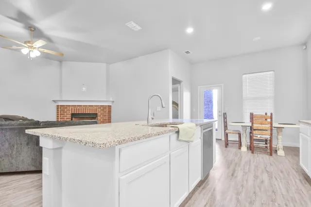 a room with kitchen island a sink dishwasher a dining table and chairs with wooden floor