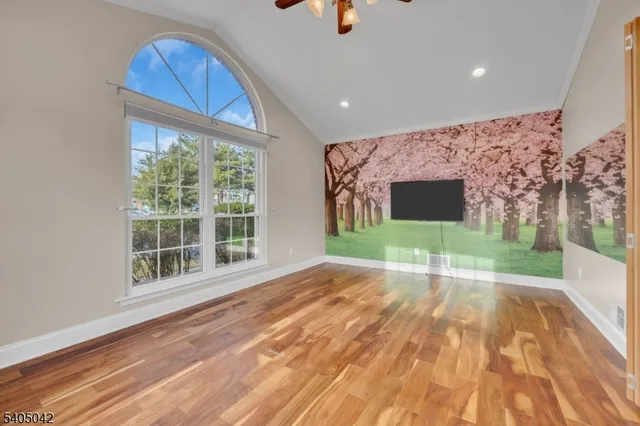 a view of an empty room with wooden floor and stairs