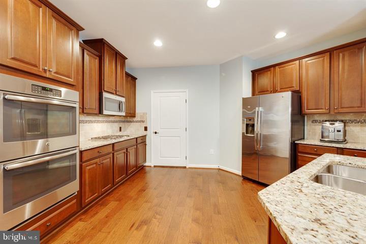 24876 Helms Terrace Aldie, VA 20105 - Photo 11 of 45 a kitchen with stainless steel appliances granite countertop a refrigerator a stove top oven and sink