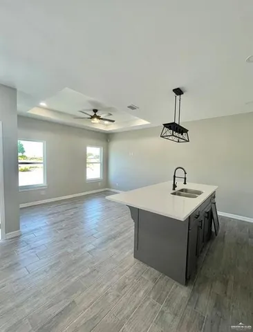 a kitchen with stainless steel appliances granite countertop a sink dishwasher a stove and a dining table with wooden floor