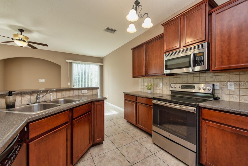7525 Red Mill Circle New Port Richey, FL 34653 - Photo 11 of 41 a kitchen with stainless steel appliances granite countertop a sink stove and microwave