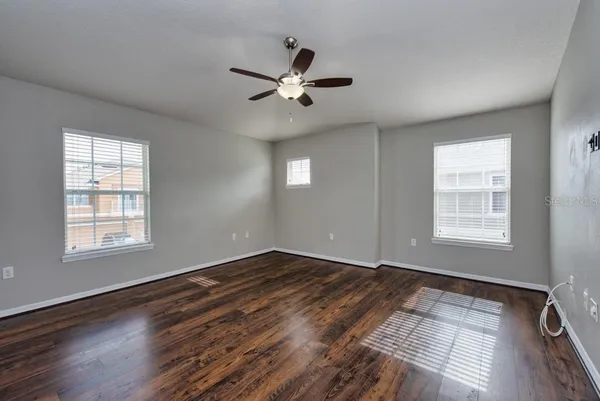 a view of empty room with wooden floor and fan