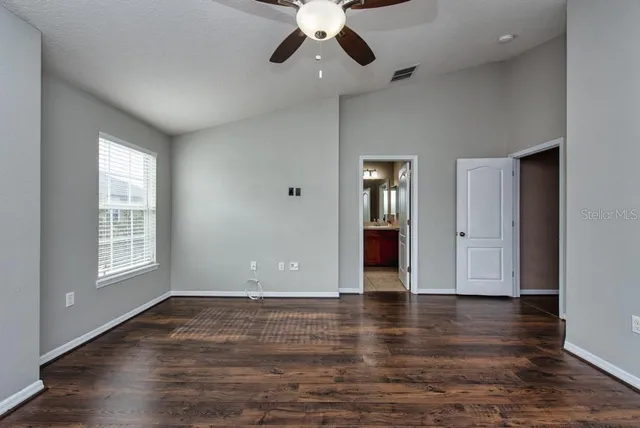 an empty room with wooden floor chandelier and windows
