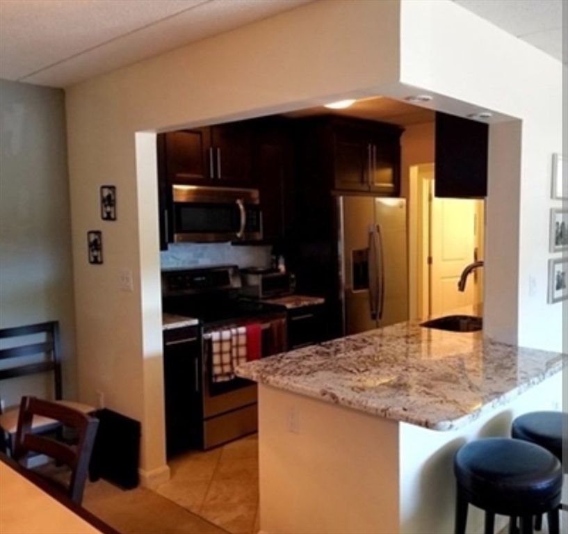 40 Main Street, Unit 308 Stoneham, MA 02180 - Photo 2 of 10 a kitchen with kitchen island a counter top space cabinets and stainless steel appliances