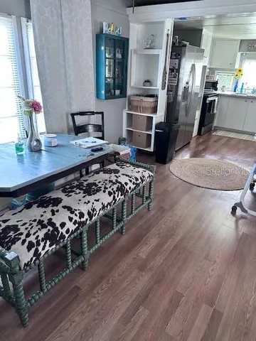 a living room with stainless steel appliances furniture a rug and a view of kitchen