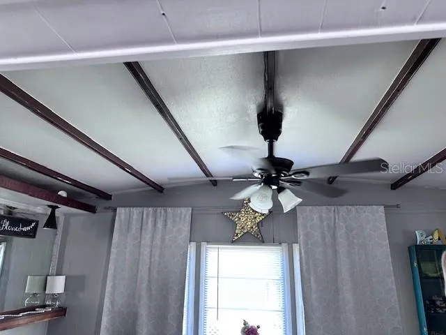 a room with a chandelier fan and wooden floor