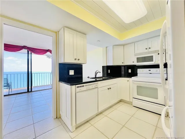 a kitchen with granite countertop white cabinets and black appliances