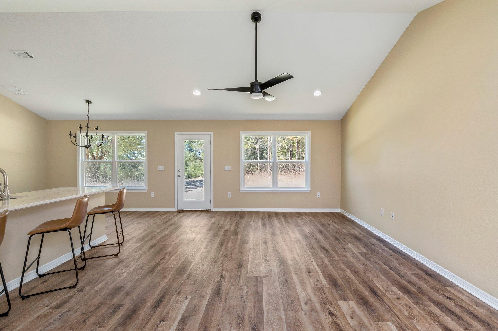 6014 Sand Hill Road Crestview, FL 32539 - Photo 8 of 41 a view of a room with wooden floor a ceiling fan and windows