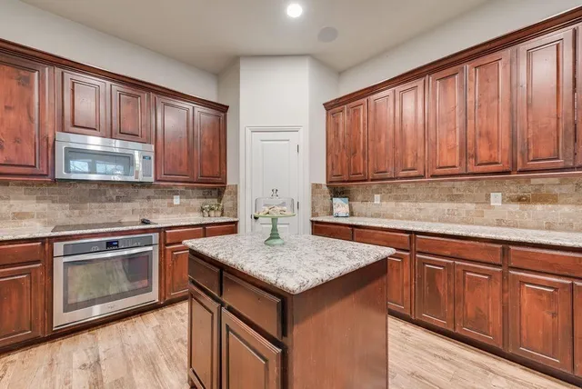 a kitchen with stainless steel appliances granite countertop wooden cabinets and a stove top oven