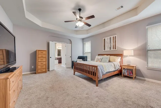 a spacious bedroom with a bed couch tv and a window