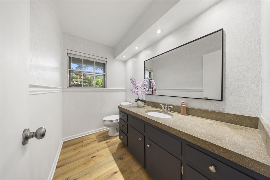 3060 Timberview Road Dallas, TX 75229 - Photo 18 of 39 Bathroom with wood-finish flooring, white beadboard wainscoting, and textured upper wall covering