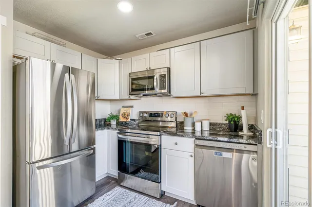 a kitchen with stainless steel appliances granite countertop a refrigerator sink and microwave