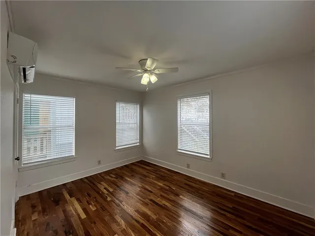 a view of an empty room with wooden floor and window