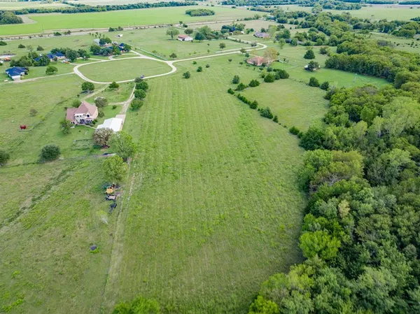 an aerial view of a residential houses with outdoor space and trees