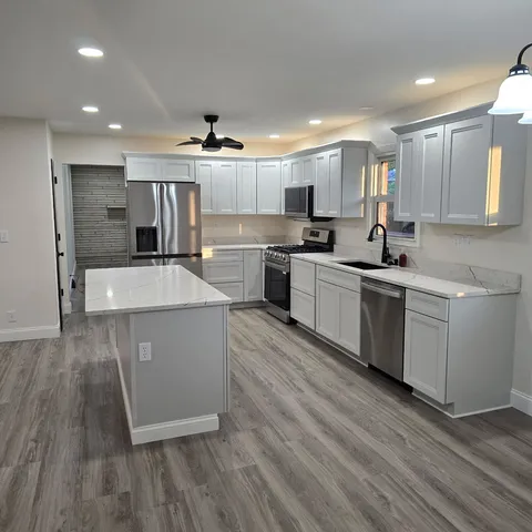 a large kitchen with stainless steel appliances kitchen island a large counter top a sink and a stove