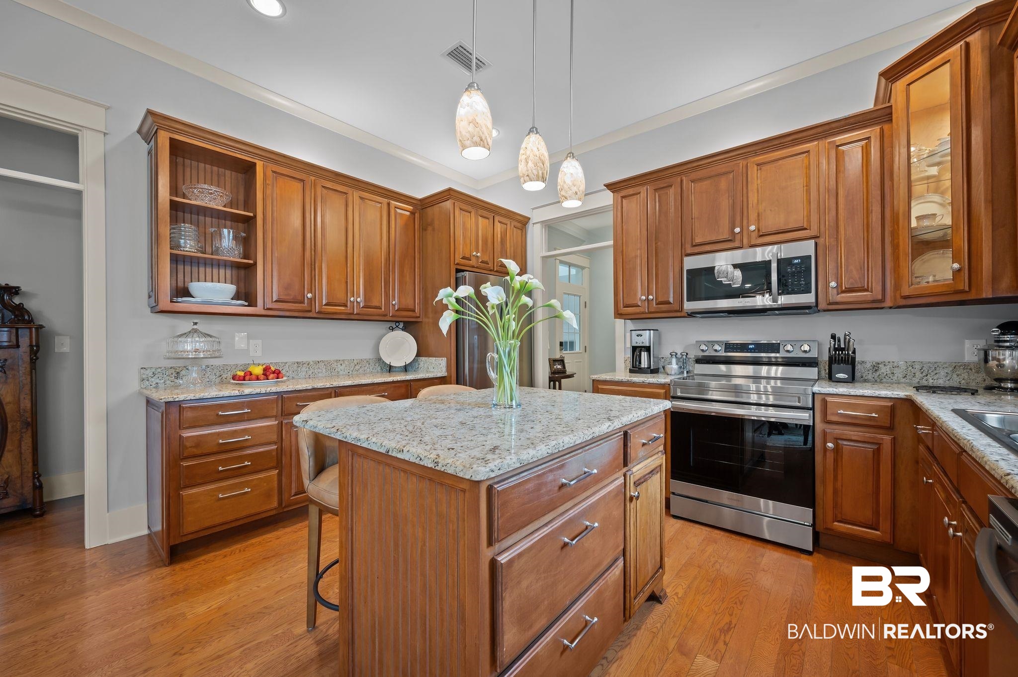 905 Buttercup Lane Foley, AL 36535 - Photo 23 of 47 Kitchen featuring appliances with stainless steel finishes, a kitchen island, hanging light fixtures, brown cabinetry, and crown molding