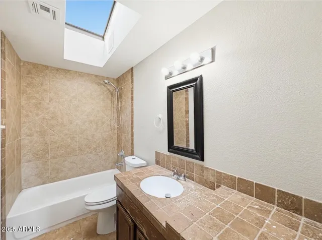 a bathroom with a granite countertop sink mirror vanity and toilet