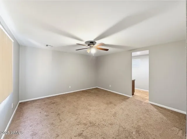an empty room with a fan & a window