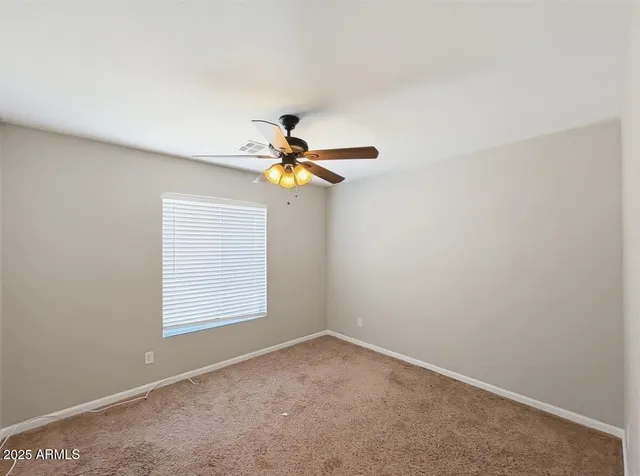 an empty room with a window and a fan