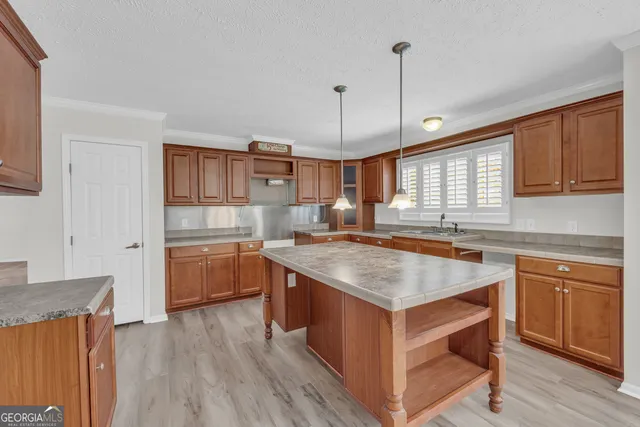a kitchen with kitchen island granite countertop a sink stove and wooden cabinets